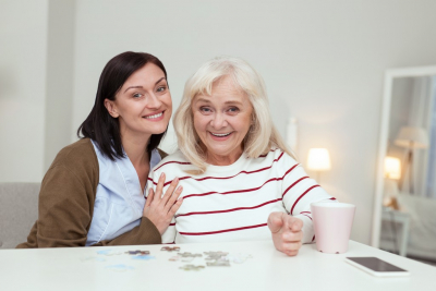 female caregiver and her old woman patient playing puzzle