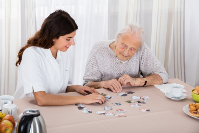 female caregiver and her old woman patient solving the puzzle