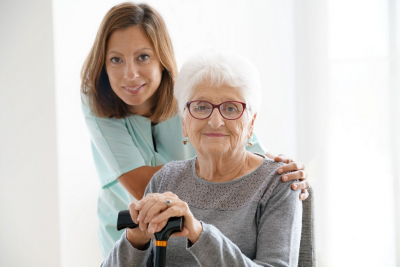 smiling female caregiver and her old woman patient wearing eye glasses